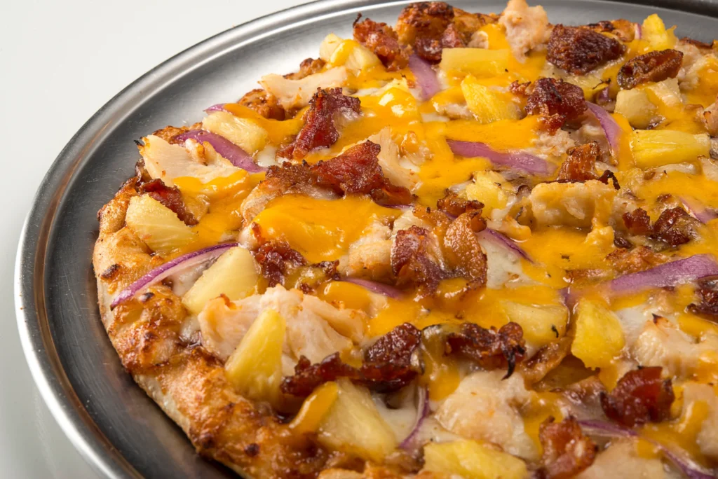 Pizza topped with bacon, pineapple, cheese, and savory sauce