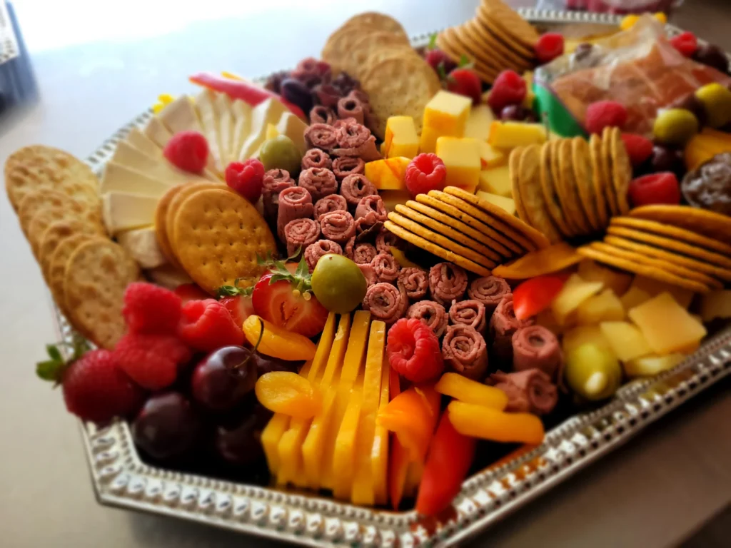 Colorful charcuterie platter with meats, cheeses, fruit, and crackers