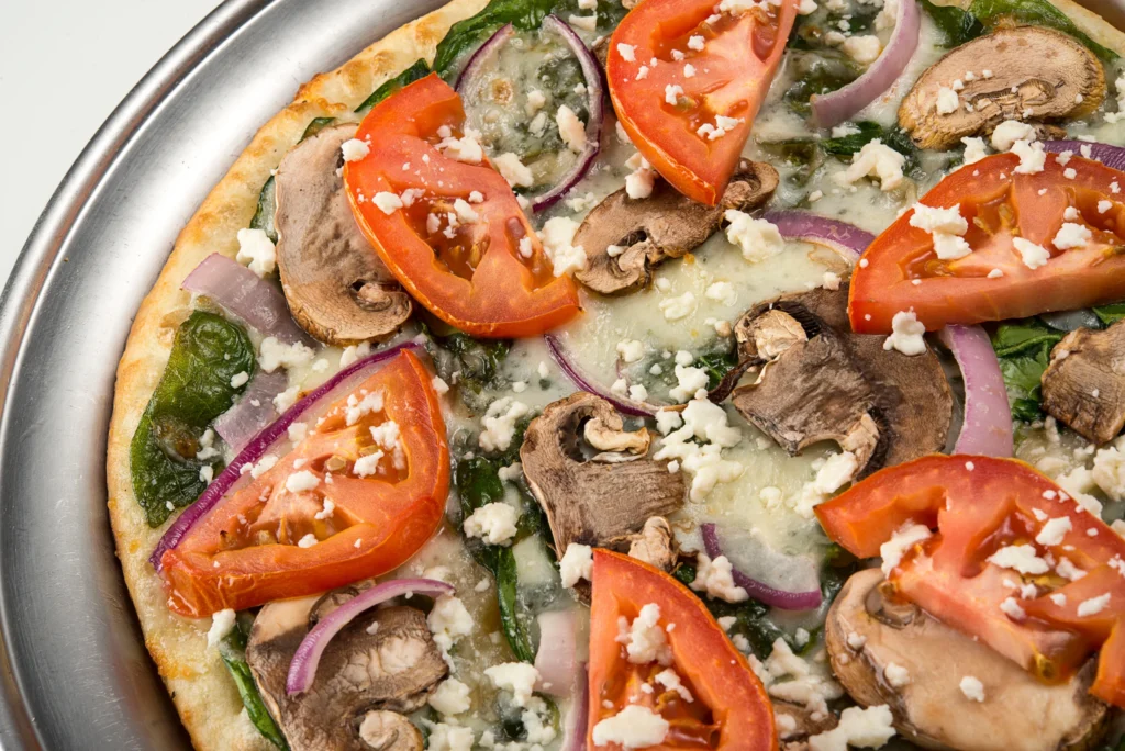 Pizza topped with mushrooms, tomatoes, onions, cheese, and herbs