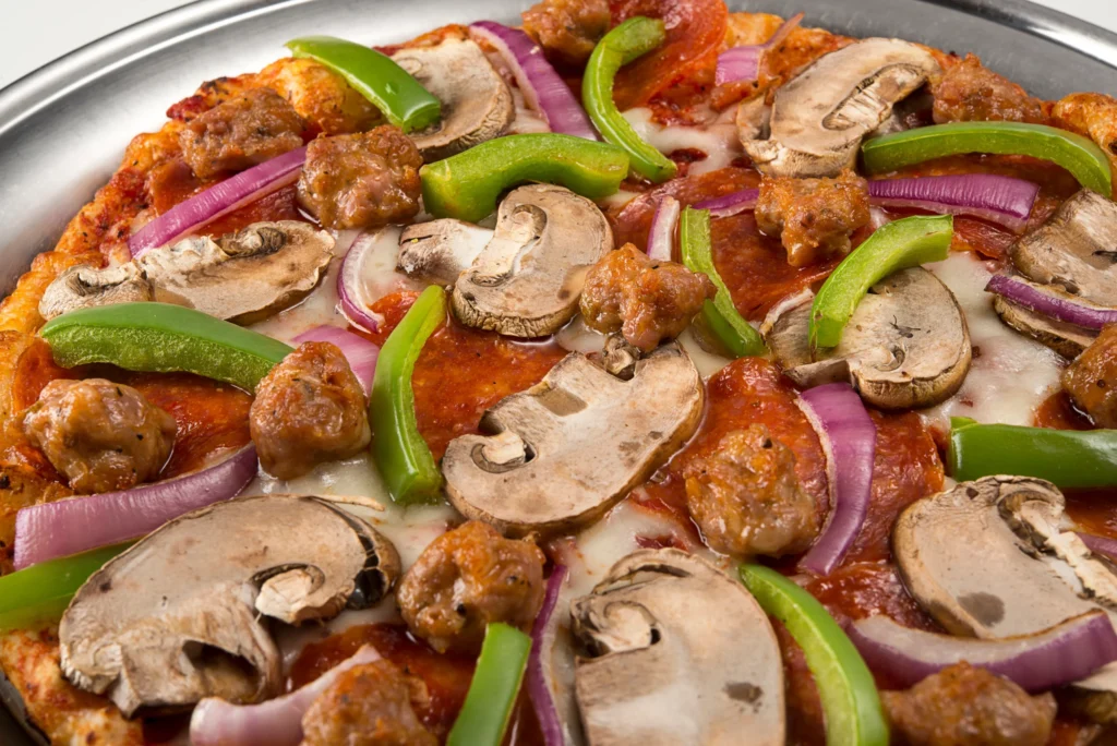 Pizza topped with sausage, mushrooms, onions, peppers, and pepperoni